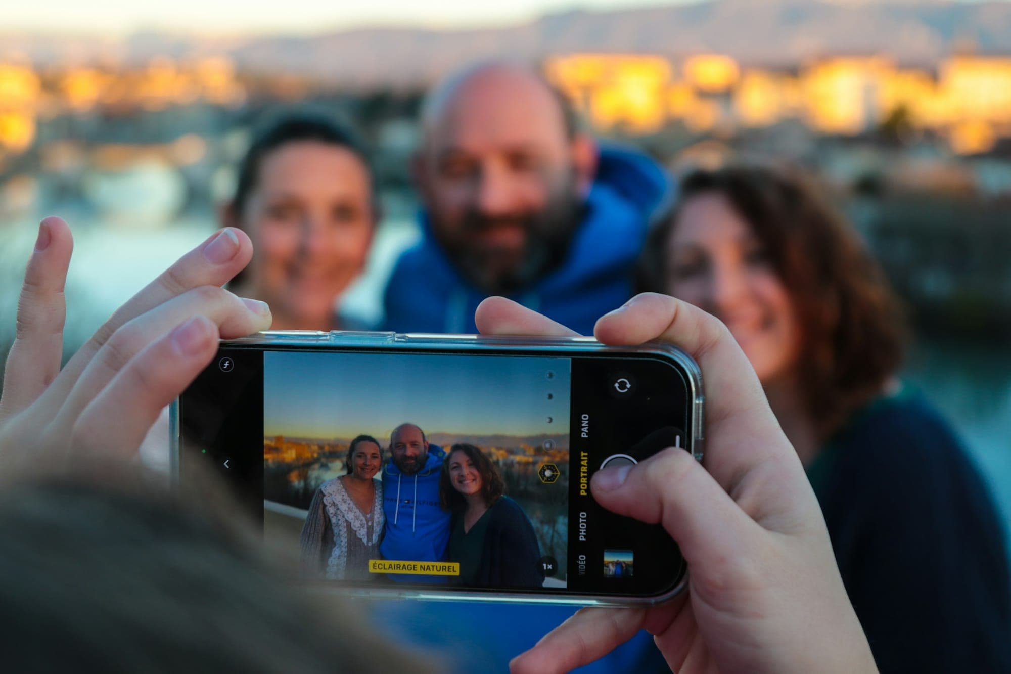 Ein Familienfoto am Wasser wird mit dem Smartphone aufgenommen