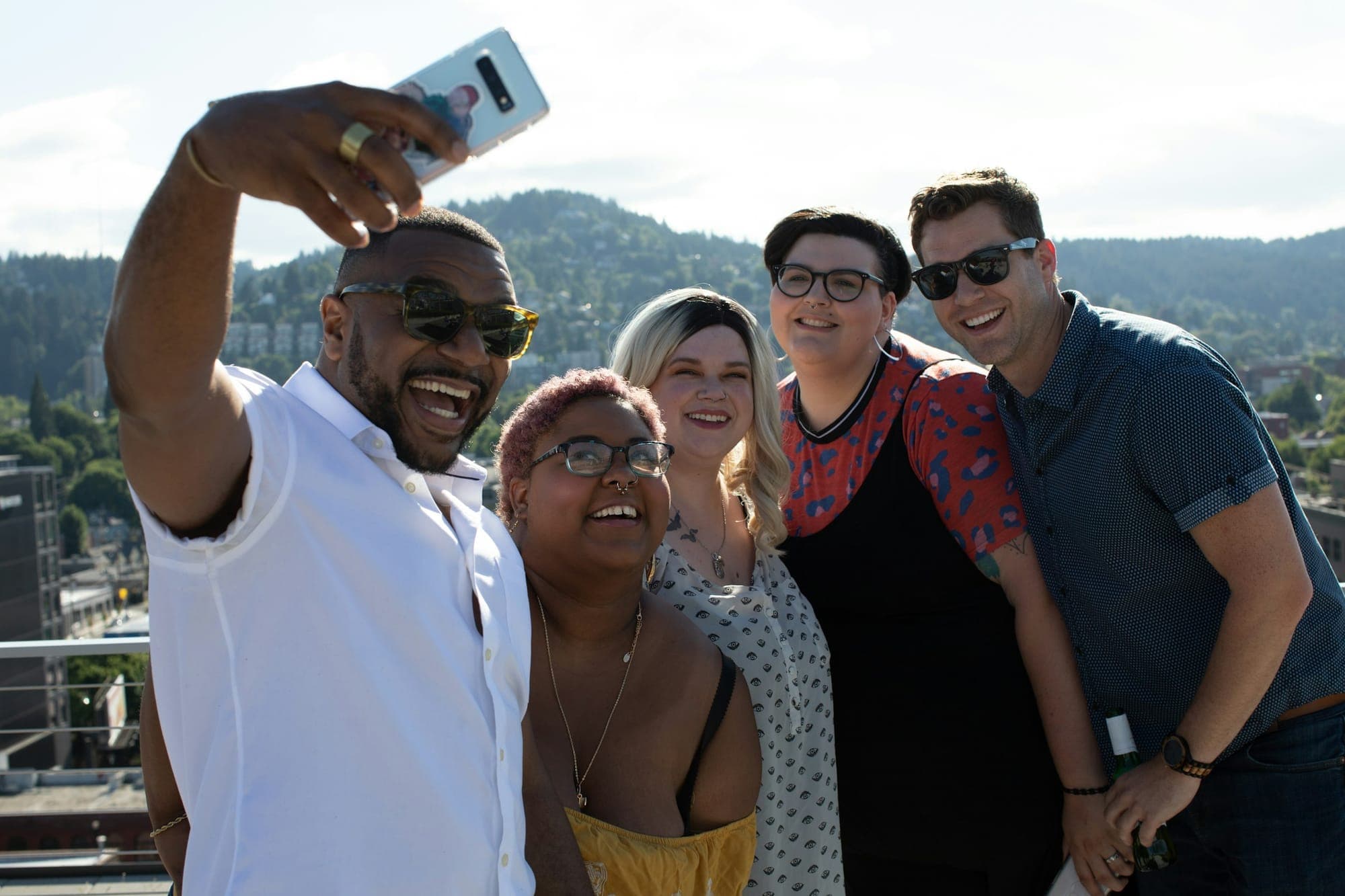 Gruppe macht auf einer Dachterrasse ein Selfie mit dem Smartphone